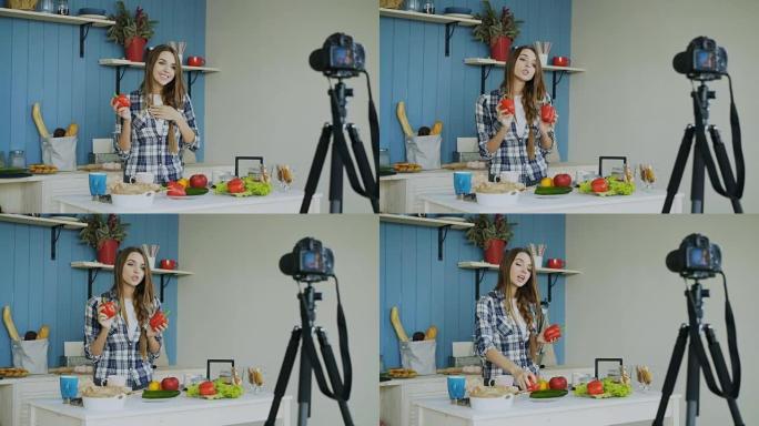 开朗迷人的女人在家里厨房的dslr相机上录制关于素食健康食品的视频博客