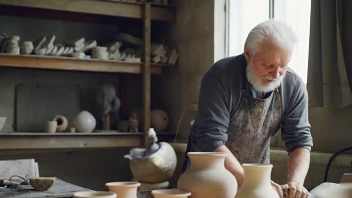 经验丰富的陶工正在车间的工作台上揉捏粘土。创造食道、手工器皿和专业陶器概念。