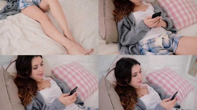 使用无线技术的年轻女子躺在床上在家聊天。智能手机上的女孩类型使用触摸屏