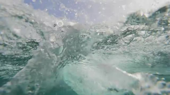 水下: 冲浪者花花公子雕刻出清澈的波浪，并在他周围泼水。