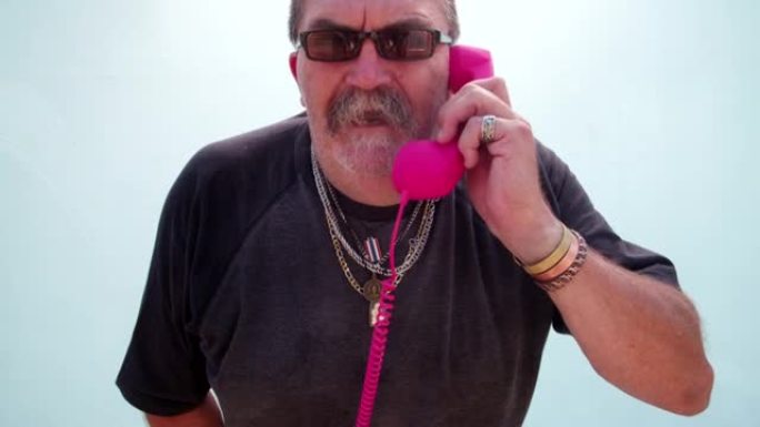 有趣的愤怒的老人拿着粉红色的手机