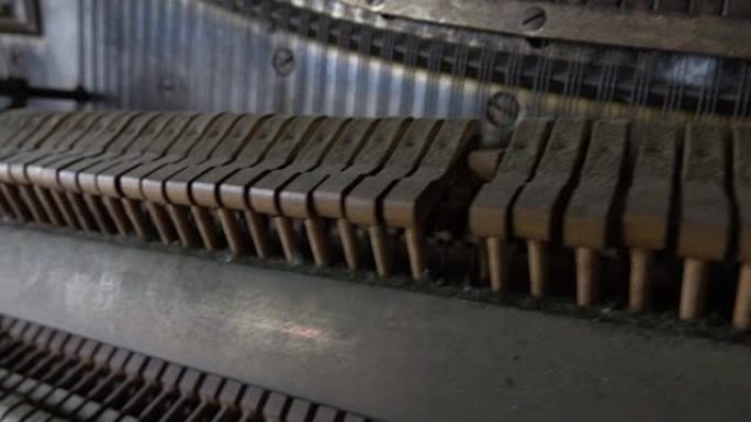 特写: 尘土飞扬的锤子在旧被毁的钢琴中敲击弦的细节