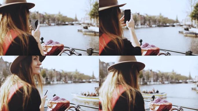 骑自行车的旅游小姐在桥上拍照。长发和花朵的女性拍摄美丽的河流风景