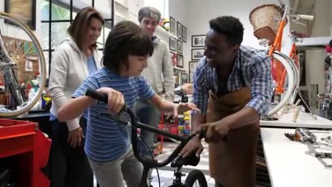男孩和他的父母和友好的推销员在一家自行车商店里，让他尝试他的第一辆自行车，看上去很兴奋