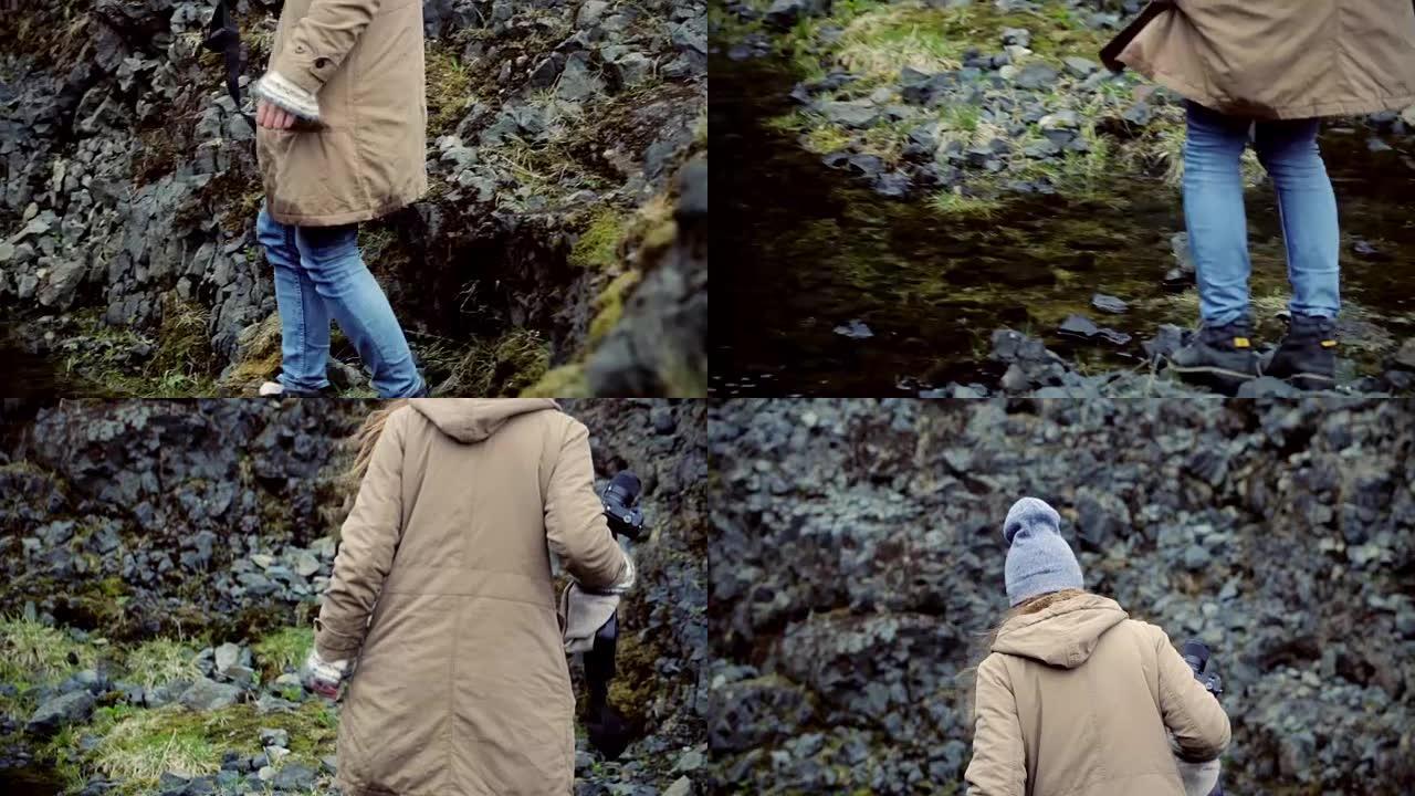 年轻的旅游女子拿着相机，在河边的山上徒步旅行。独自探索风景的女孩