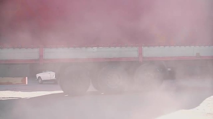 一辆红色货车向右转。空气中的尘埃云
