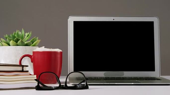 笔记本电脑，眼镜，一杯咖啡和一堆书