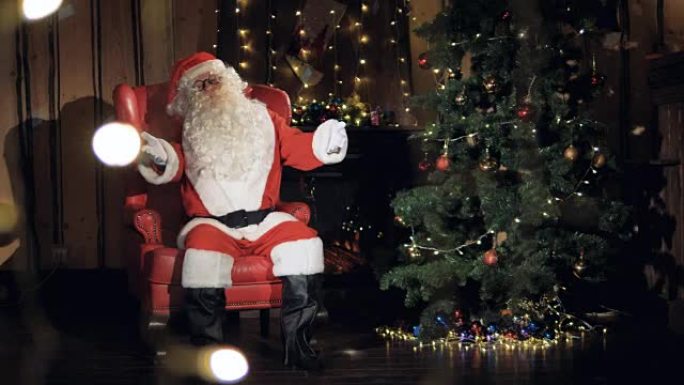 令人愉悦的圣诞老人坐在圣诞树前的椅子上。