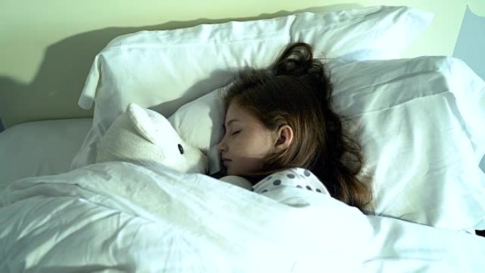 可爱的小女孩和泰迪熊睡在床上。