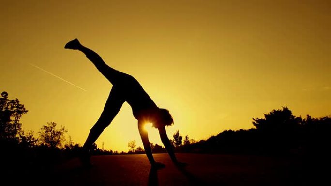慢动作: 年轻女子在日落时做体操轮