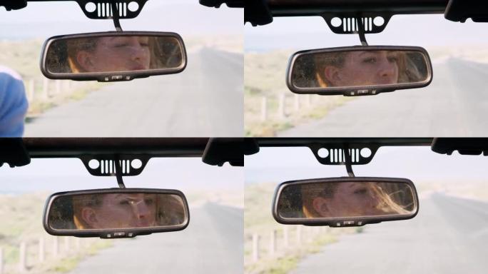 年轻女子的脸反映在驾驶汽车的镜子中