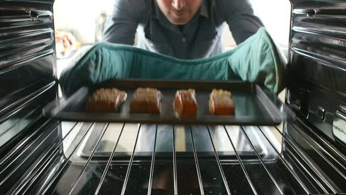 男子从烤箱中取出煮熟的鲑鱼片托盘