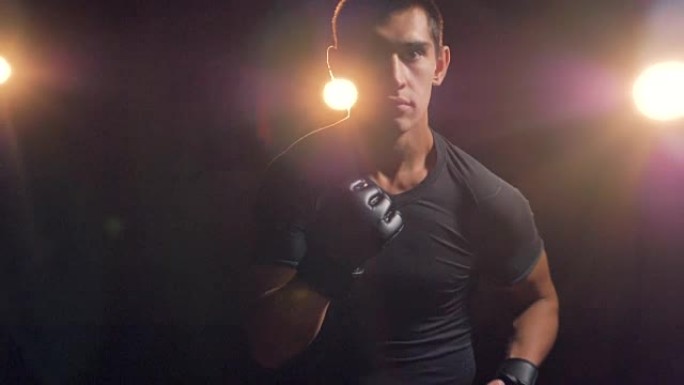 一个男性拳击手在黑暗中展示他的拳头。