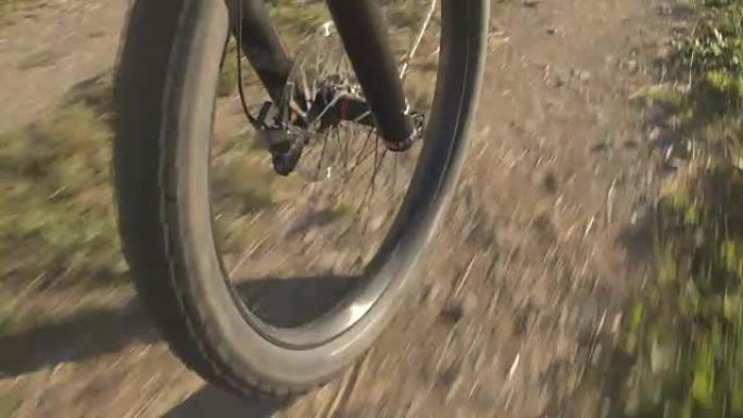 特写: 电动自行车车轮和大山地自行车轮胎在砾石路径上快速旋转