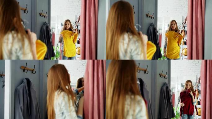 年轻女士在试衣间挑选衣服的镜子镜头。女孩正在尝试上衣和套头衫，站在大镜子对面时检查它们的大小和长度。
