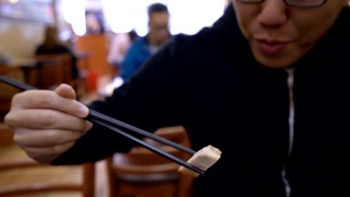男人用筷子吃中国脆皮五花肉
