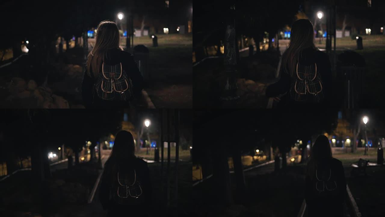 深夜穿过黑暗公园的年轻时尚女性的后景。晚上独自去