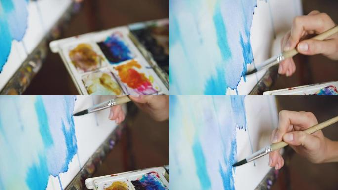 年轻女性艺术家用水彩颜料和画架画布特写手画笔