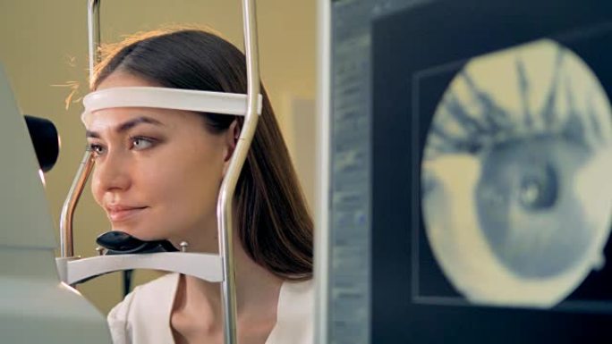 一名妇女将头放在视网膜摄像头的下巴上。
