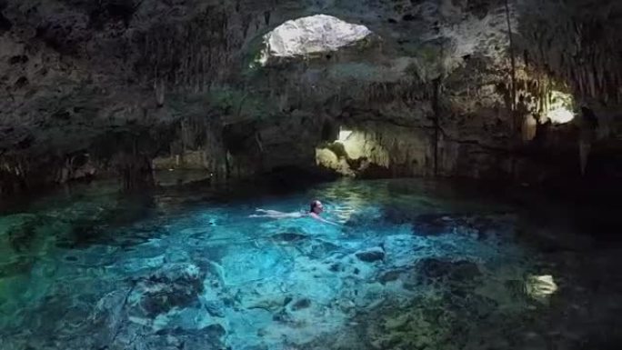 特写女孩在令人惊叹的cenote污水坑游泳和探索绿松石池