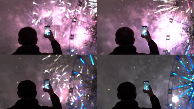 观看和拍摄烟花的男子特写镜头的慢动作在户外智能手机相机上爆炸