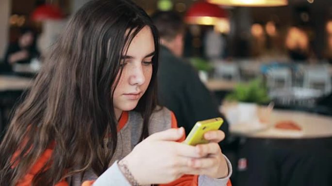 在咖啡馆使用智能手机的少女