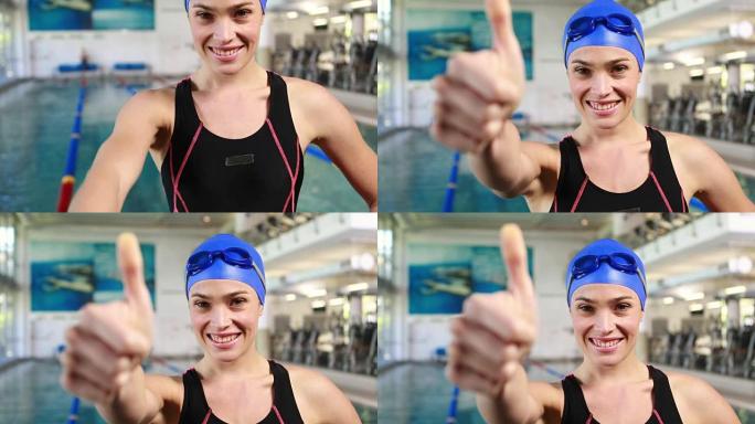 微笑的女游泳者竖起大拇指