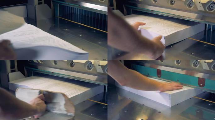 一名工人将纸张放入切纸工业机器的特写镜头。4K。