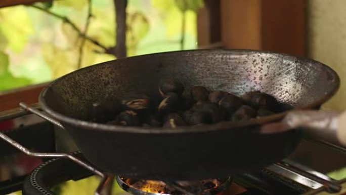 栗子在火焰上在铸铁煎锅中烘烤，慢动作