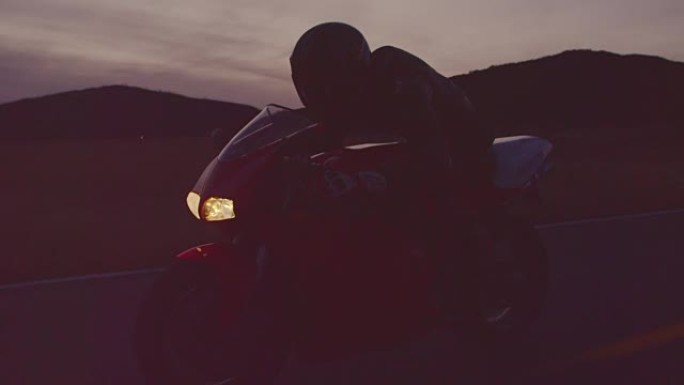 慢动作男子在黄昏时骑着摩托车，前灯开着