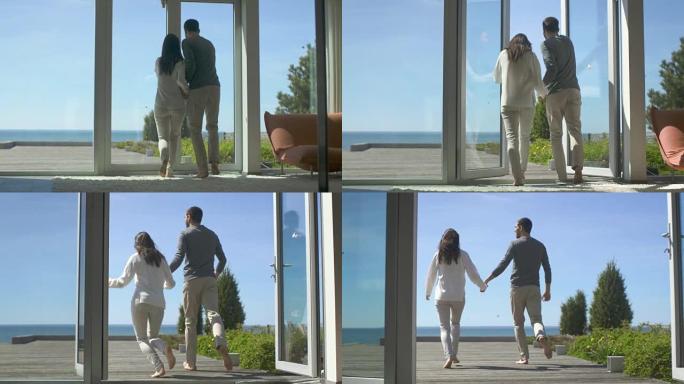 拍摄了一对美丽的夫妇打开阳台门，走进阳光明媚的露台，可以看到海边的景色。天空万里无云，人们快乐。