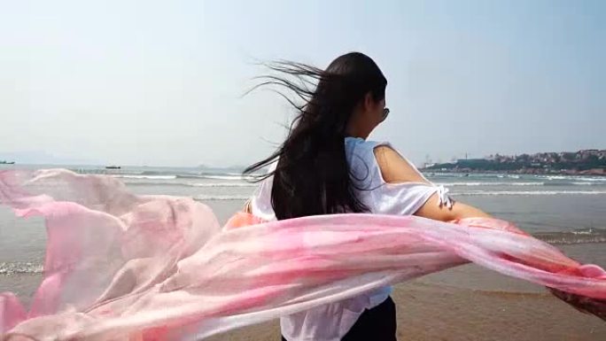 戴着围巾在海边散步的女人