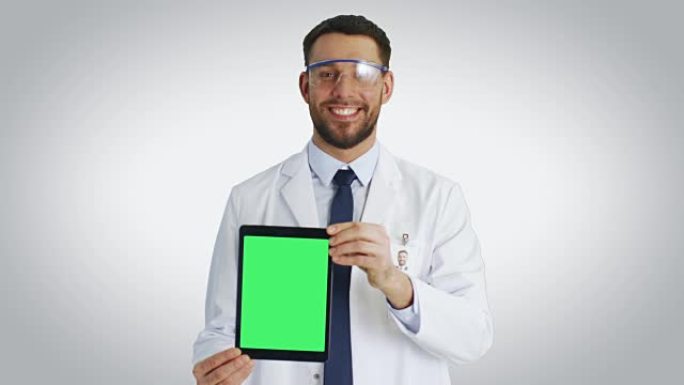 一位微笑的科学家向美国平板电脑展示了带有孤立模型绿屏的镜头。以白色背景拍摄。