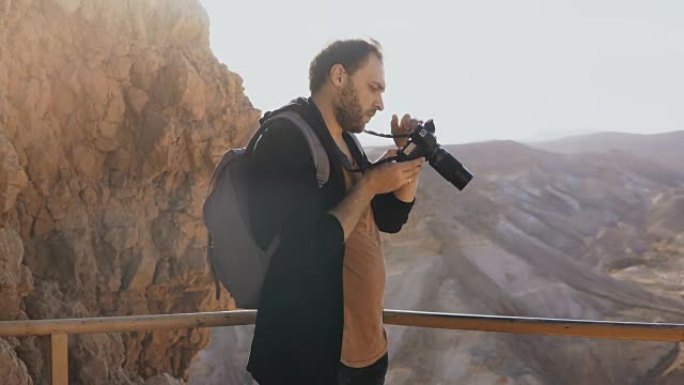 男人拍了大片山景的照片。白人男性拿着相机照片，看着他的相机。以色列4K