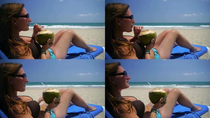 女孩在海滩上喝椰子汁
