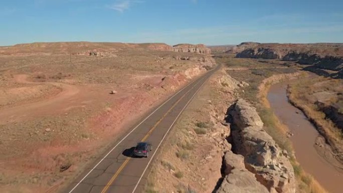 空中: 黑色SUV汽车沿着蜿蜒的空旷道路穿越峡谷谷