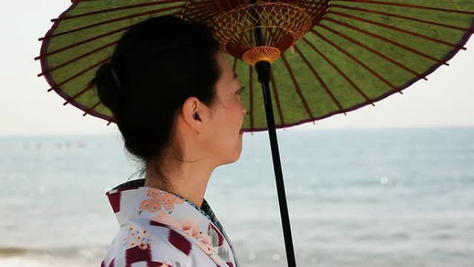 日本女人拿着遮阳伞享受大海