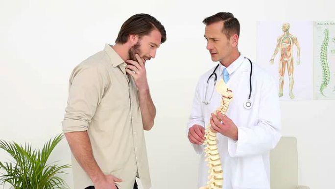 医生和他的病人谈论骨骼脊柱模型
