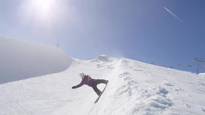 慢动作: 年轻的专业滑雪者在阳光明媚的雪地公园的半管壁上滑动