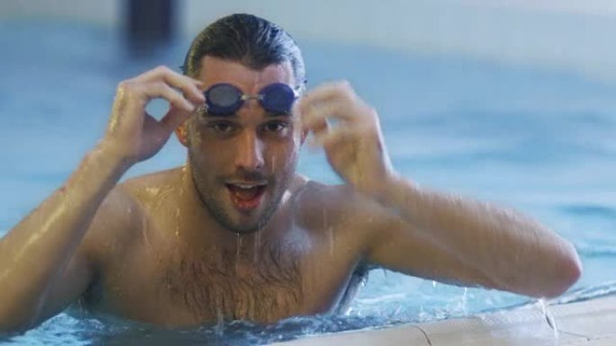 戴护目镜的专业游泳者在游泳池里出水