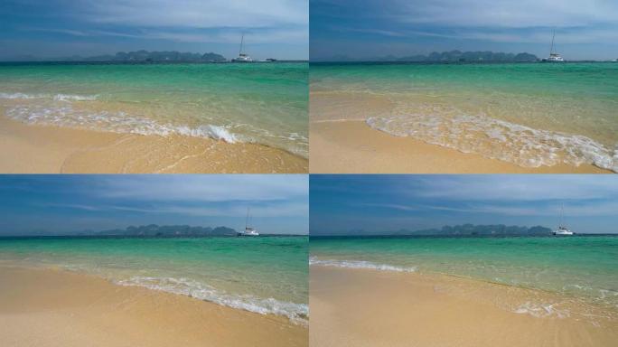 海滩有白色的沙子和清澈的蓝色的水。游艇停泊在珊瑚岛附近