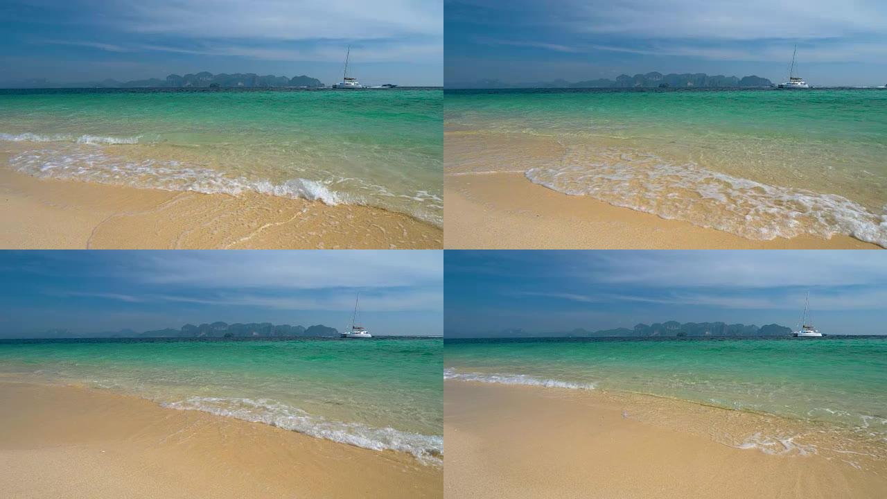 海滩有白色的沙子和清澈的蓝色的水。游艇停泊在珊瑚岛附近