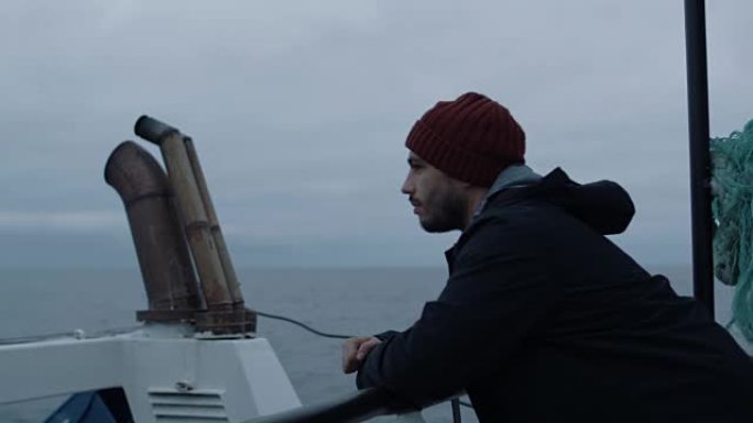 Serios Man站在船上，看着大海。