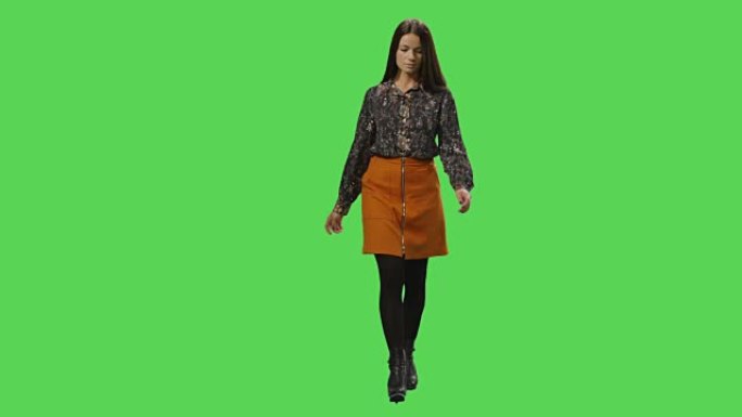 休闲的年轻黑发女孩正走在背景的模拟绿屏上。