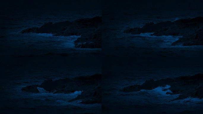 海浪在夜间在岩石上破裂