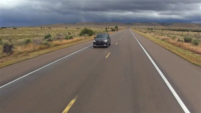 天线: 黑色SUV汽车在恶劣的阴雨天气在潮湿的空旷的乡村道路上行驶