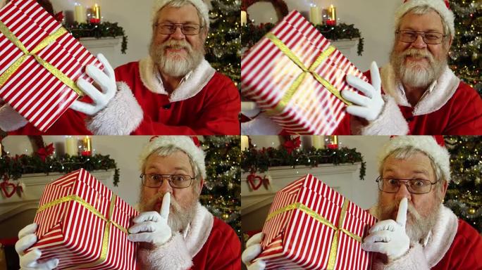 圣诞老人拿着手指放在嘴唇上的礼品盒的肖像