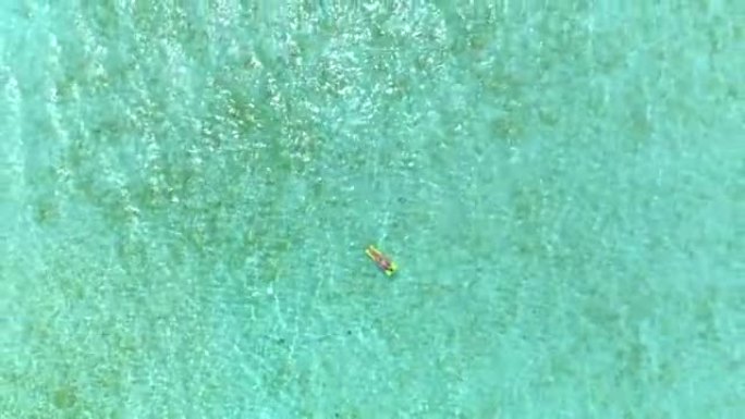 4K天线:快乐的年轻女子穿着比基尼躺在充气床垫上，在广阔的海洋中度过她有趣的暑假