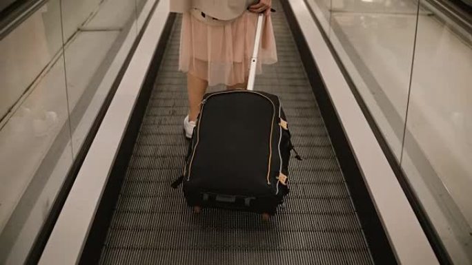 站在机场自动扶梯上的年轻女子的特写镜头。时髦的女性准备去旅行