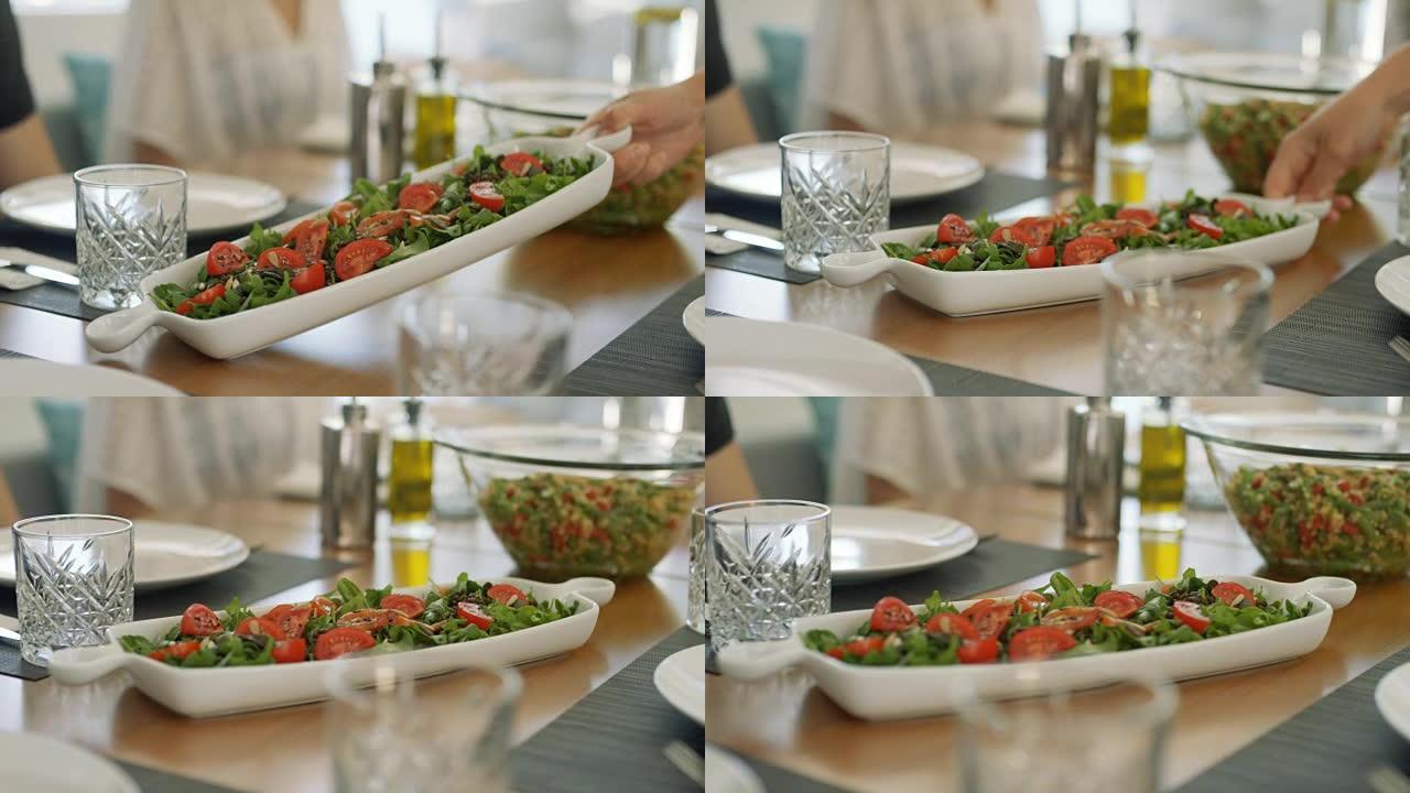 服务员将新鲜时令沙拉的碗和其他健康菜肴放在桌子上。